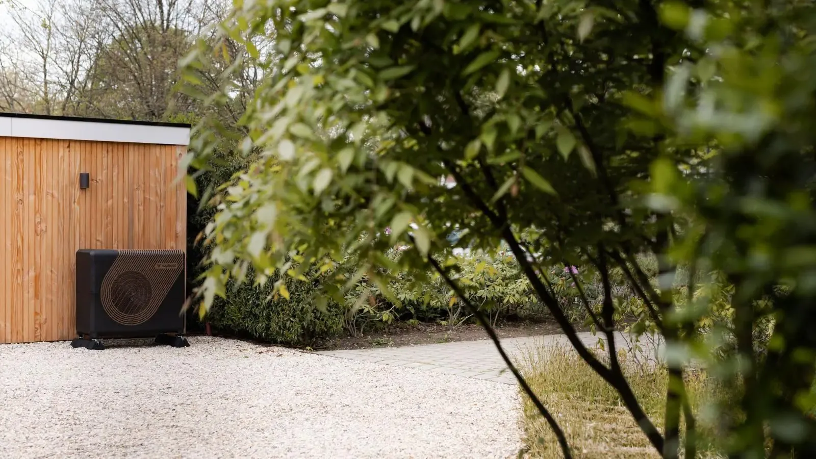 Buitenunit van een warmtepomp in de tuin van een woning
