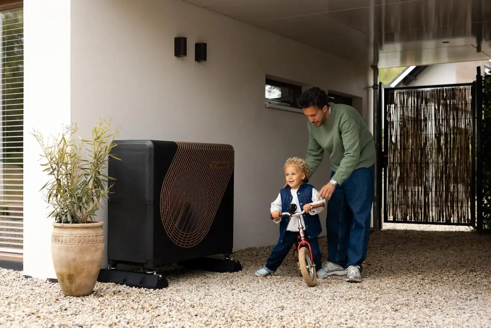 Vader en zoon in de tuin bij de buitenunit van een warmtepomp